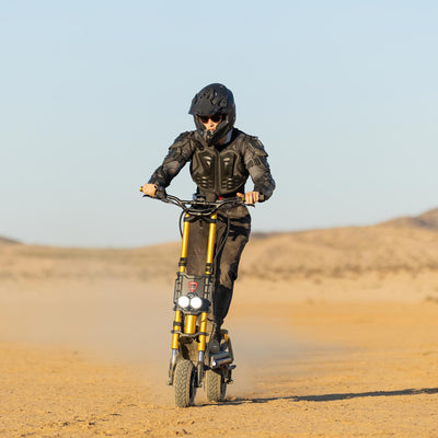 Rider on a Kaabo King GTR electric scooter driving off-road in desert terrain, showcasing powerful dual motors and durable design for adventurous rides.