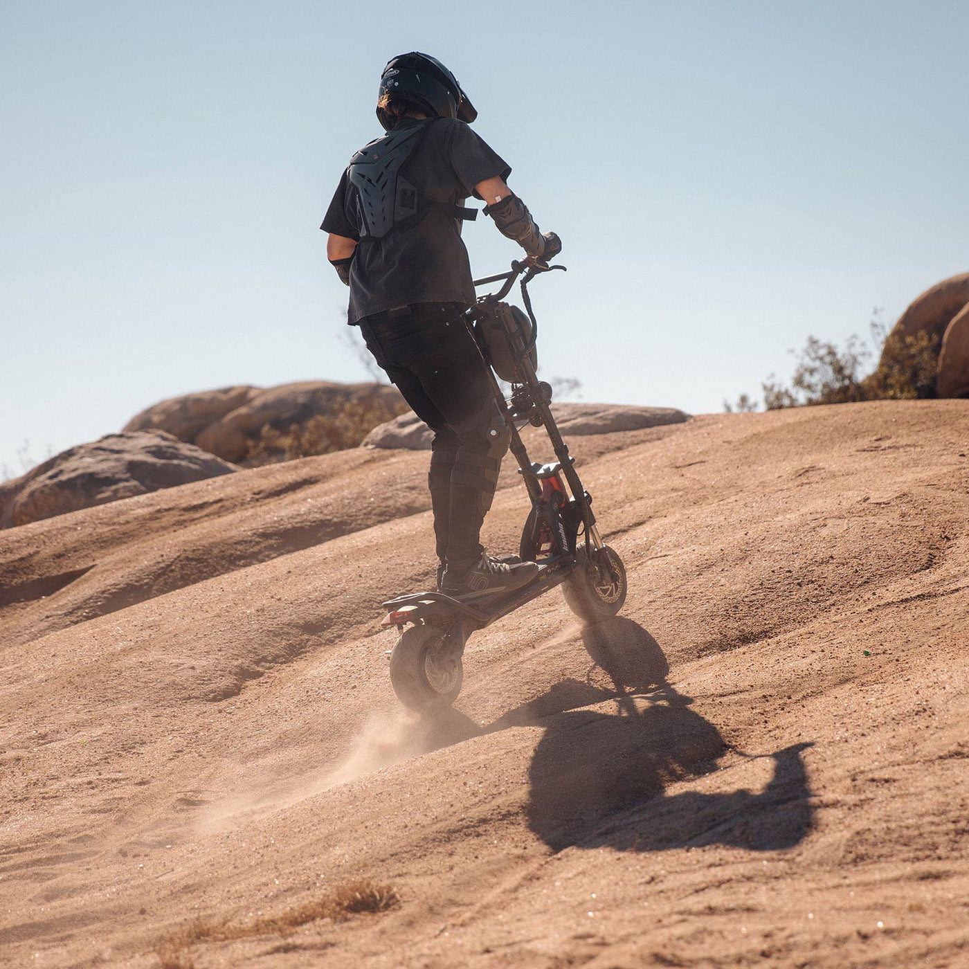 Rider conquering a steep hill with the Kaabo Warrior 11 Pro+ electric scooter, showcasing its impressive hill-climbing ability and durable design in a rugged outdoor setting.